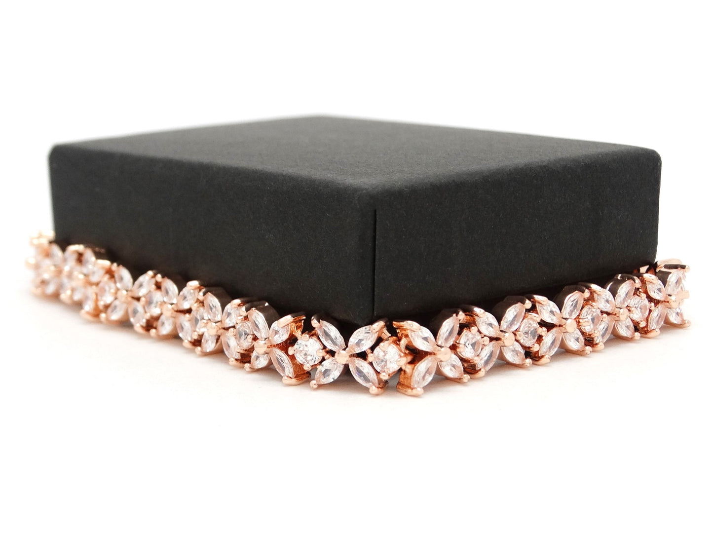 Rose gold bracelet on a black box against a white background