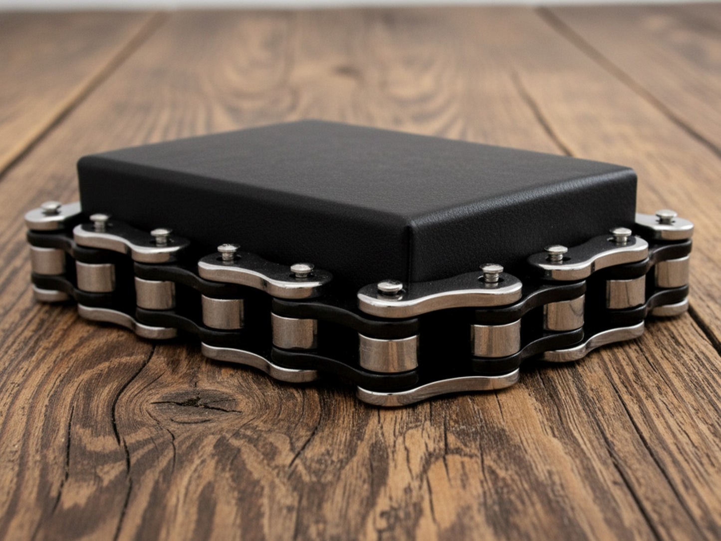 Black jewellery box with steel bike chain on a wooden surface