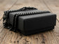 Black rectangular box with chain anklet on top, on a wooden surface