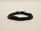 Black curb link chain anklet on a beige fabric background