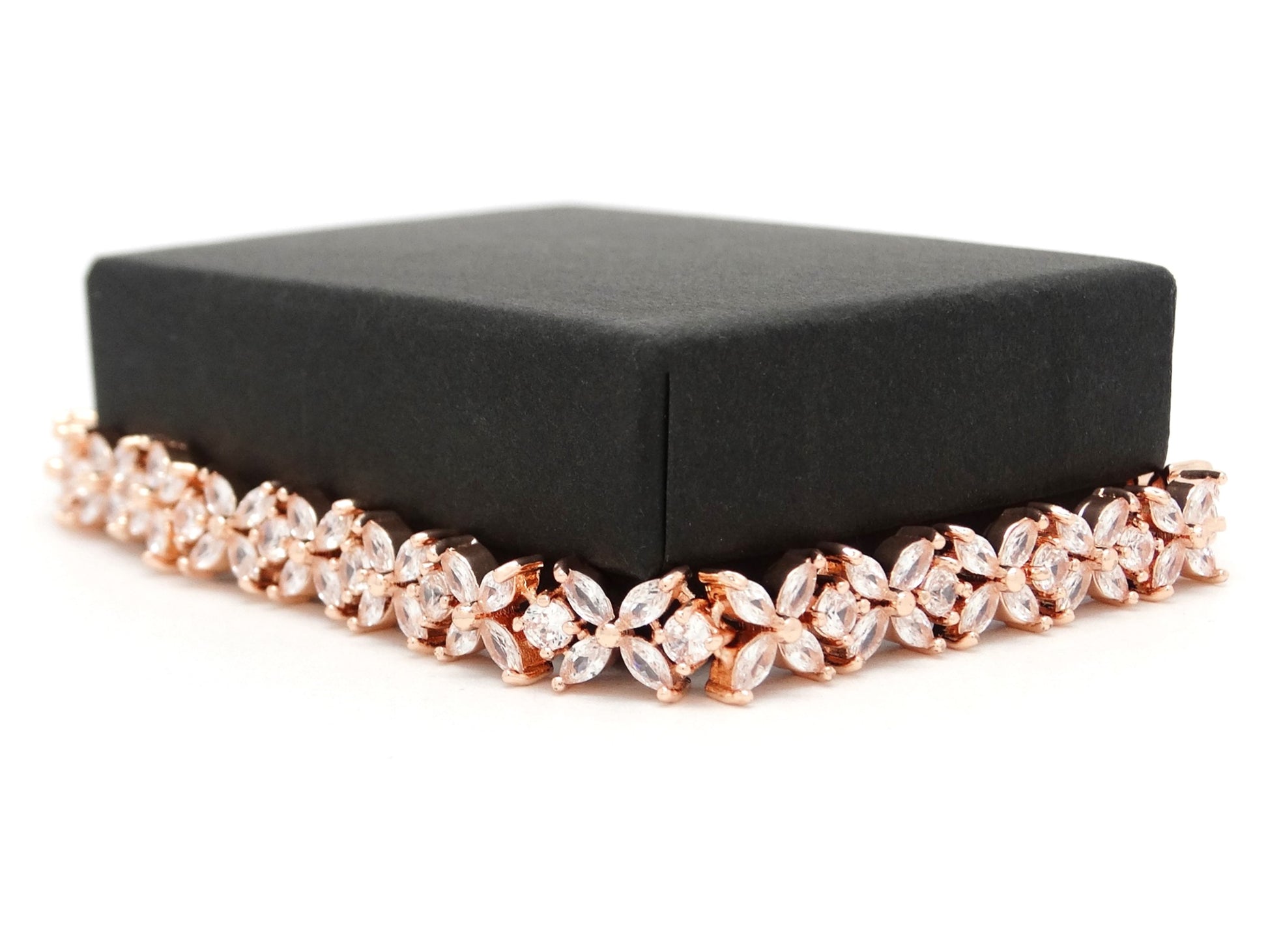 Rose gold bracelet on a black box against a white background