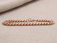 Rose gold chain bracelet on a beige fabric background