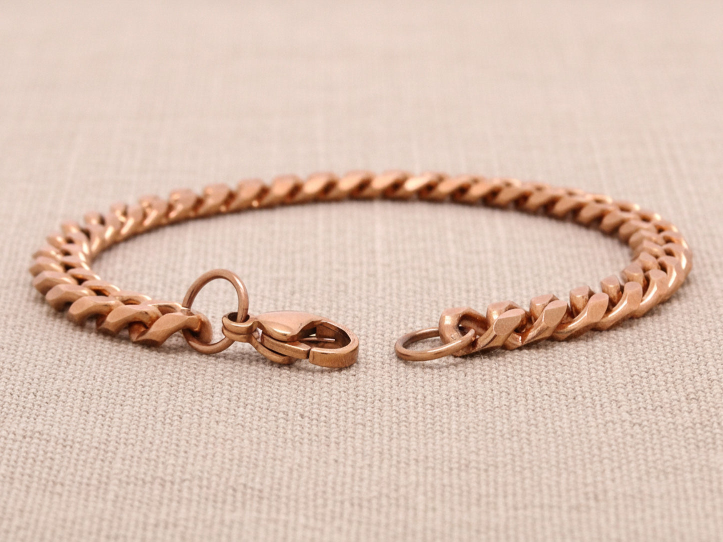 Rose gold bracelet on a beige fabric background