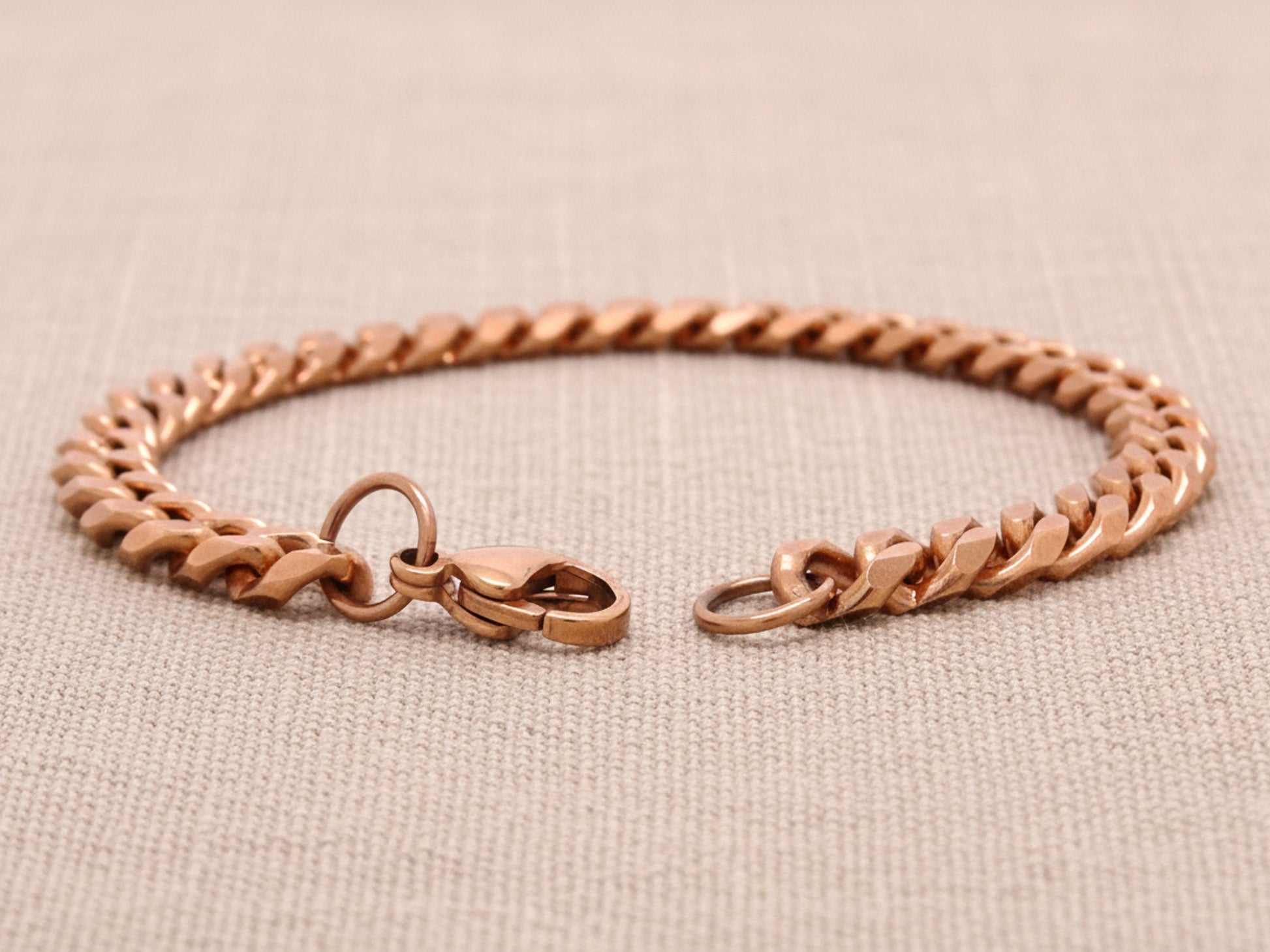 Rose gold bracelet on a beige fabric background