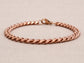 Rose gold chain bracelet on a beige fabric background