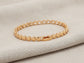 Gold bracelet on a textured beige surface