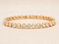 Gold bracelet with heart-shaped white gemstones on a beige background