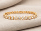 Gold bracelet with heart-shaped gemstones on a beige fabric background