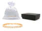 Gold bracelet with a white drawstring bag and black jewelry box on a white background