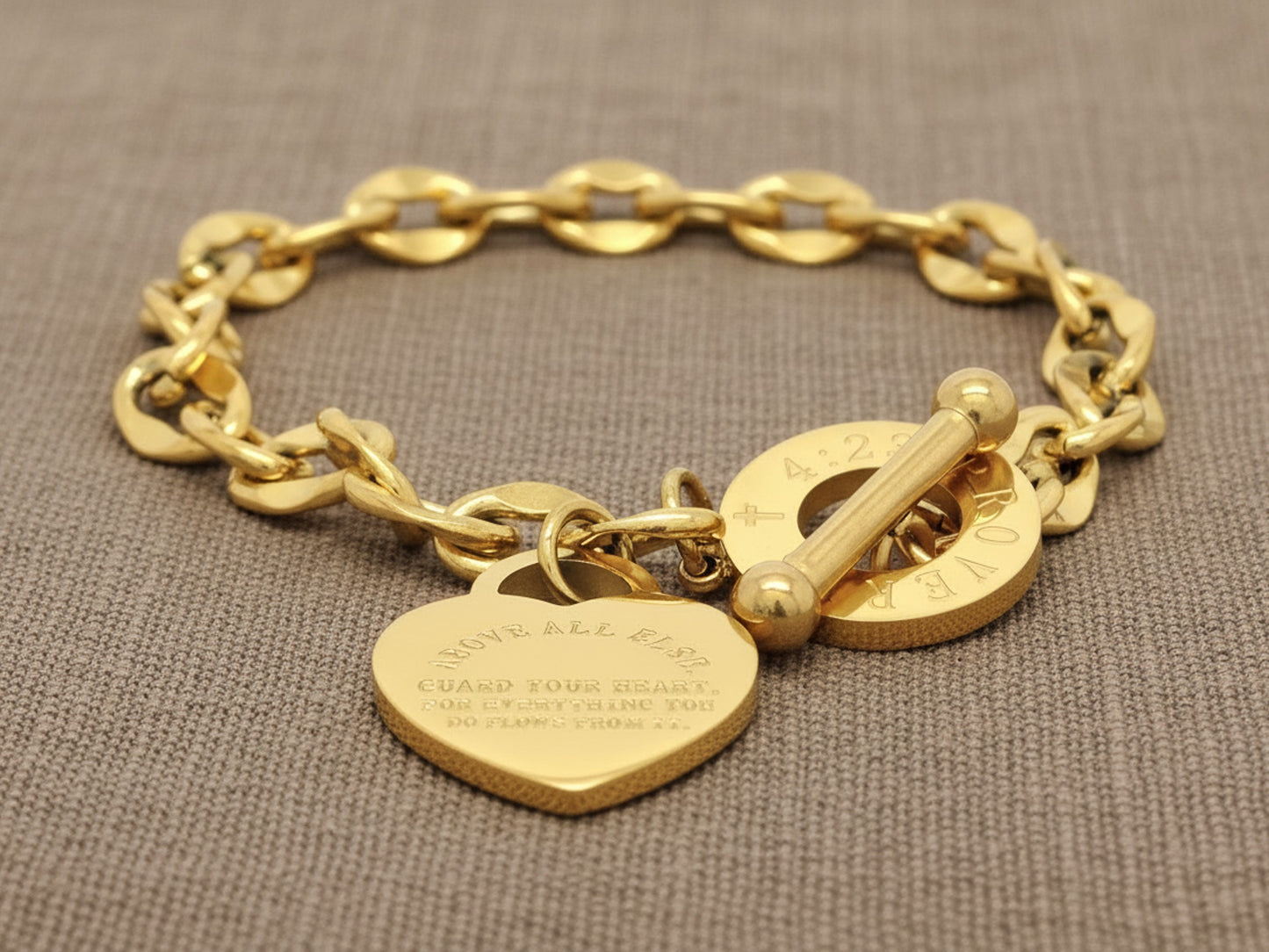 Gold chain bracelet with heart-shaped pendant on a textured brown background