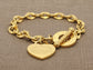 Gold chain bracelet with heart-shaped pendant on a textured brown background