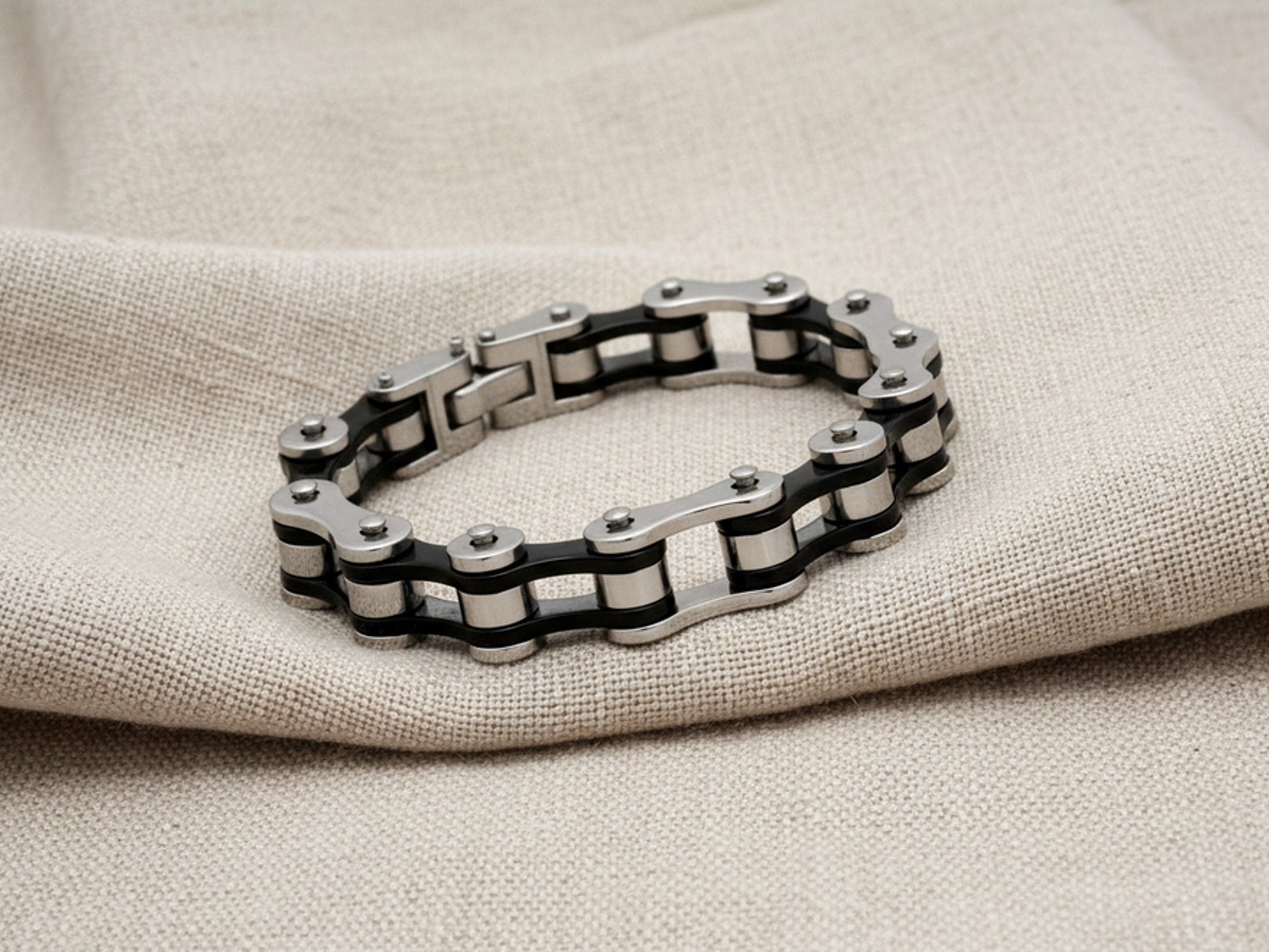 Bracelet made of interlocking metal links on a beige fabric background