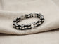 Bracelet made of interlocking metal links on a beige fabric background