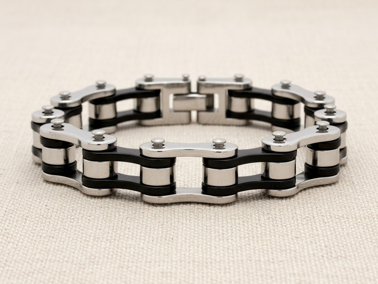 Steel bracelet with black and silver bike chain design on a beige background