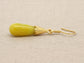 Gold earring with a yellow moonstone on a beige fabric background