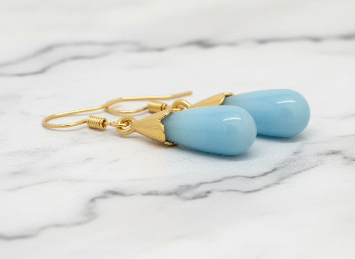 Gold earrings with blue stones on a white background