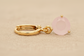 Gold earring with a pink gemstone on a beige fabric background