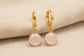 Gold earrings with pink stones on a beige fabric background