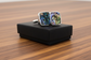 Abalone shell cufflinks on a black box with a wooden surface background