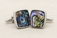 Cufflinks with abalone shell design on a beige background