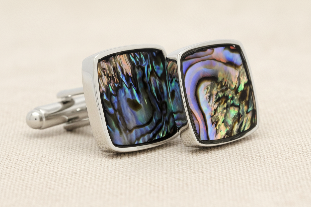 Cufflinks with abalone shell design on a beige background