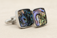 Cufflinks with abalone shell design on a beige background